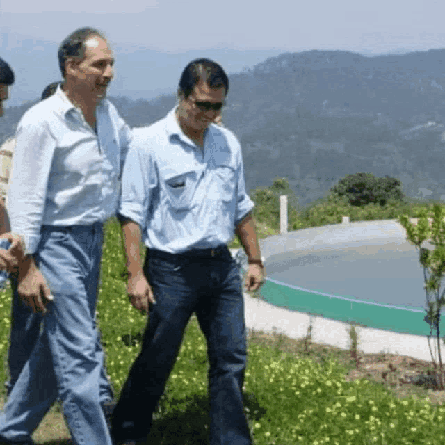 a group of men walking in a field with a pool in the background