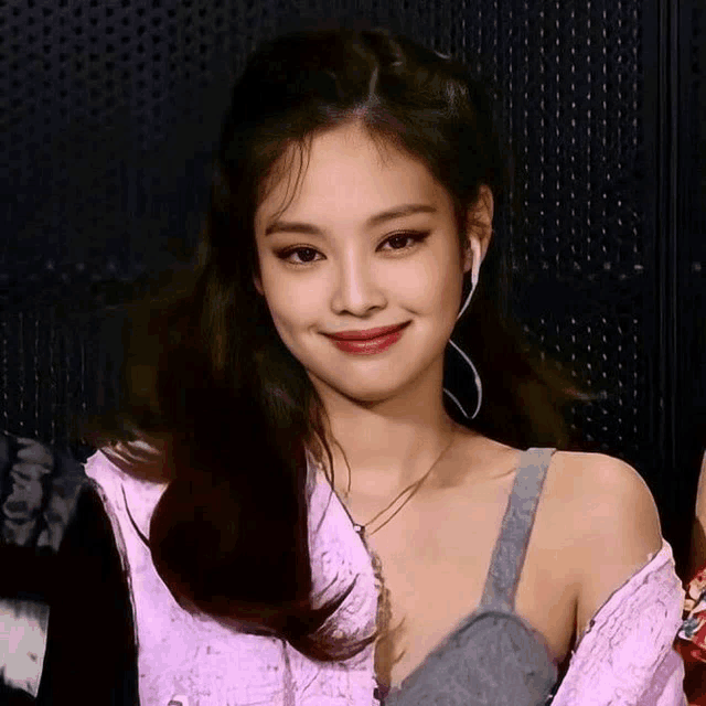 a woman wearing ear buds and a pink shirt smiles for the camera