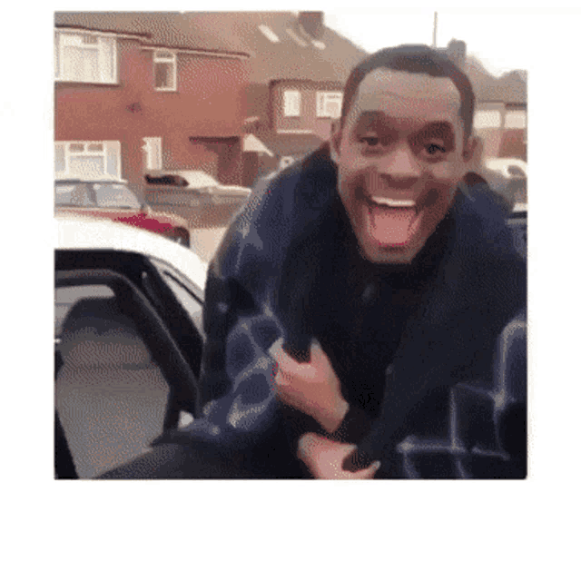 a man with his tongue hanging out is smiling while sitting in a car