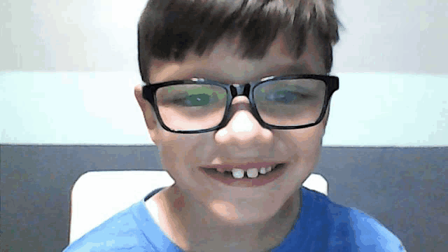 a boy wearing glasses and a blue shirt smiles for the camera