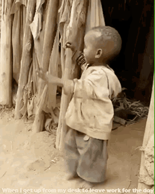 a little boy standing in front of a wooden fence with the words when i get up from my desk to leave work