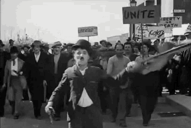 a black and white photo of a group of people marching down a street with a sign that says unite