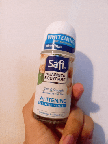 a person is holding a bottle of safi hijabista bodycare