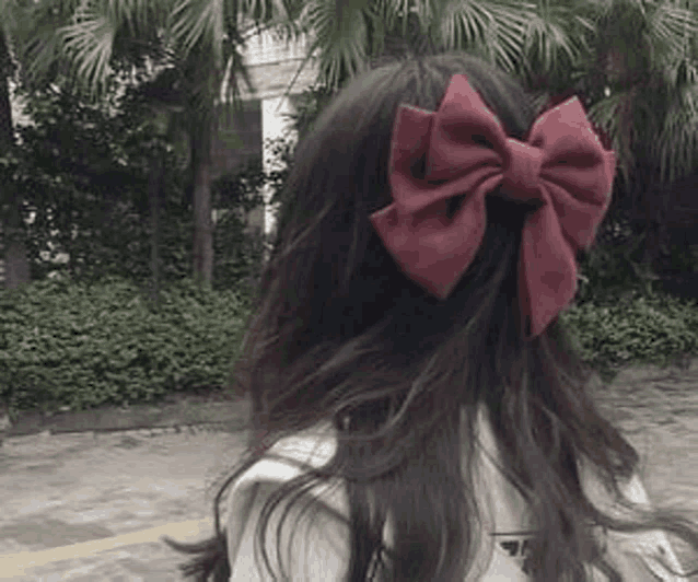 a woman with long hair and a red bow in her hair .