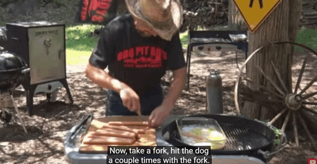 a man wearing a shirt that says bbq pit boy 's is cooking hot dogs