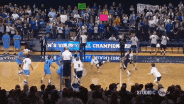 a volleyball game is being played in front of a crowd with a banner that says ' men 's volleyball '