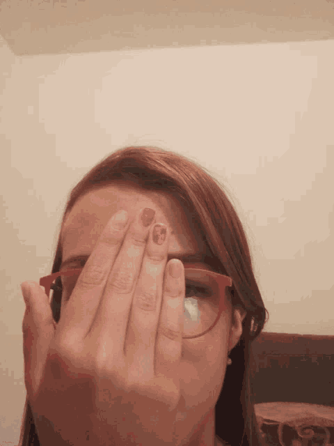 a woman wearing red glasses is covering her face