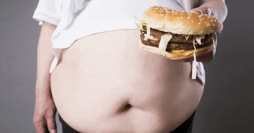 a man with a large belly is holding a hamburger in front of his belly