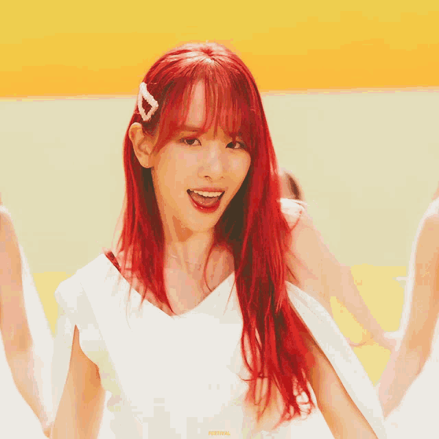 a woman with red hair is wearing a white top and a heart hair clip