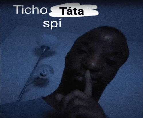 a man holds his finger to his mouth with the words " ticho tata spi " behind him