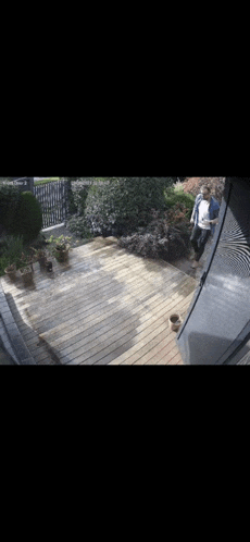 a man is standing on a wooden deck in front of a house .