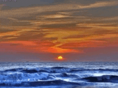 the sun is setting over the ocean with waves crashing on the beach