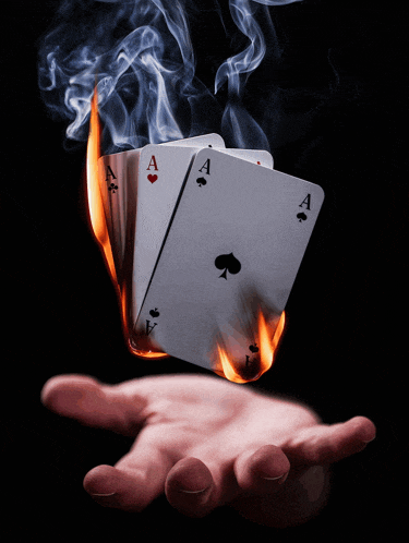 a hand holding a stack of aces on fire