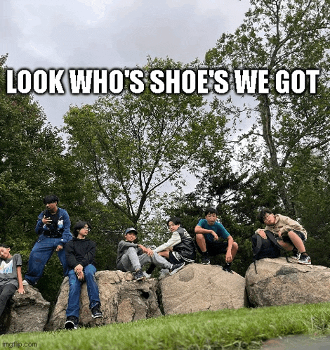 a group of young men are sitting on rocks in a park with the caption look who 's shoe 's we got