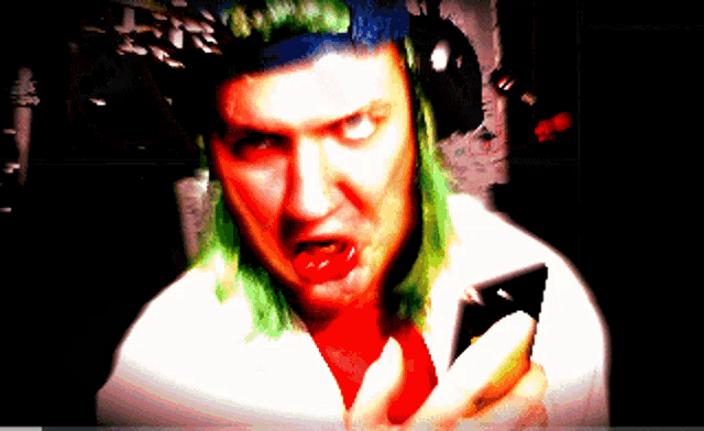 a man with green hair holds a cell phone in his hand