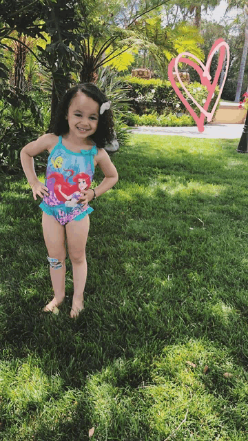 a little girl in a swimsuit with ariel on it