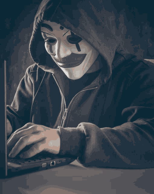 a person wearing a mask is typing on a laptop computer