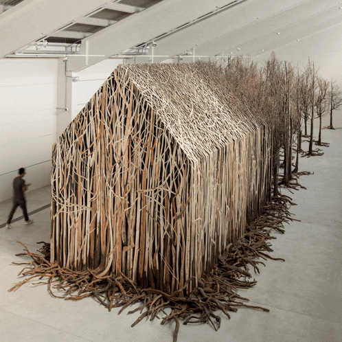 a man walks past a building made of sticks