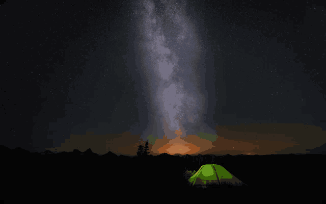 a green tent is lit up in the dark under a starry sky