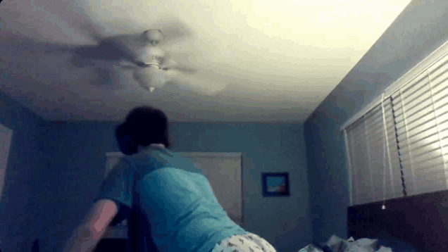 a person in a blue shirt is standing in a bedroom