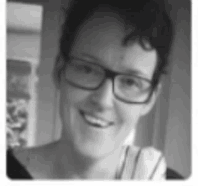 a black and white photo of a woman wearing glasses and smiling