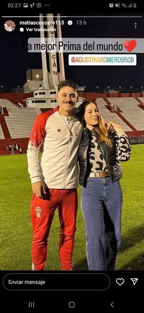 a man and a woman are posing for a picture in front of a stadium that says a mejor prima del mundo