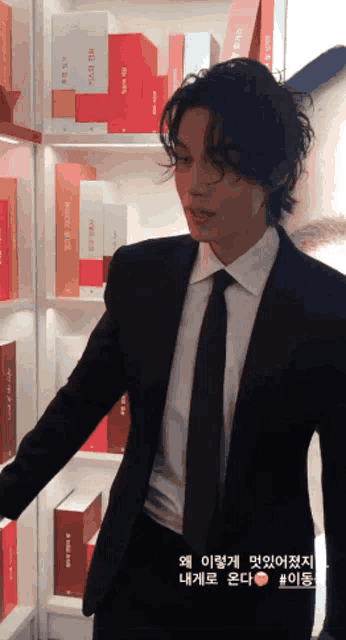 a man in a suit and tie is standing in front of a shelf with boxes on it that say ' i love you '