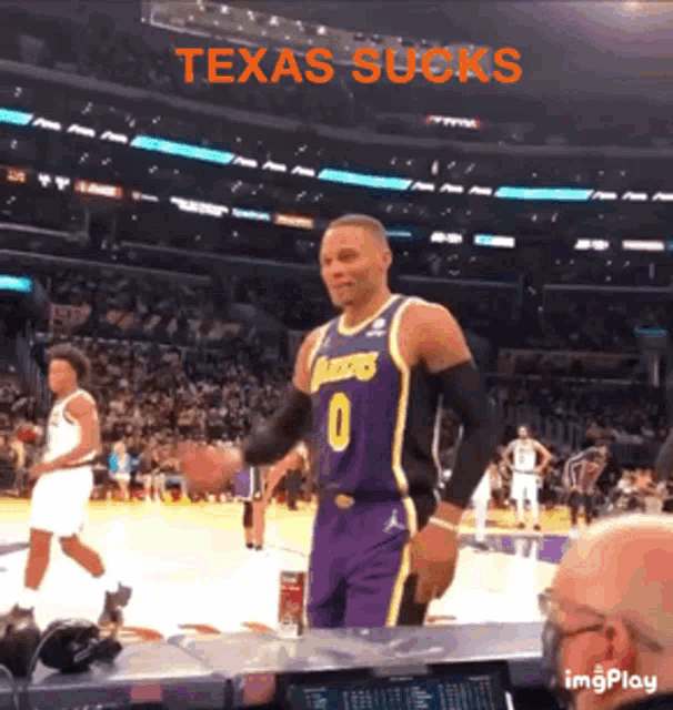 a basketball player with the number 0 on his jersey stands in front of a crowd at a basketball game