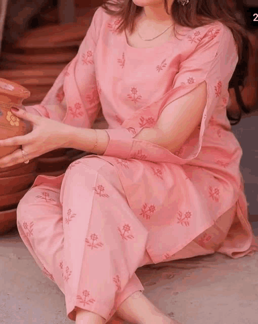 a woman in a pink dress is holding a potted plant .