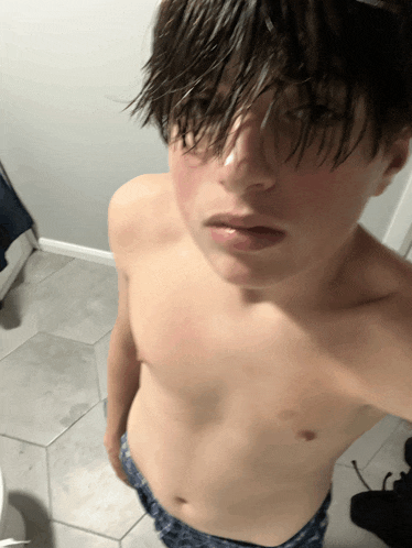 a shirtless boy taking a picture of himself in a bathroom