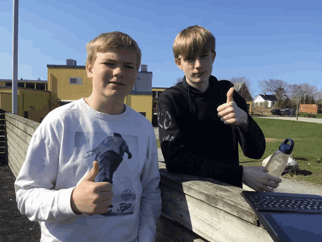 two boys giving a thumbs up with one wearing a shirt that says ' fuji '