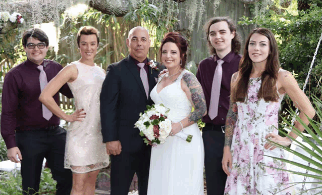 a group of people posing for a picture with the bride and groom