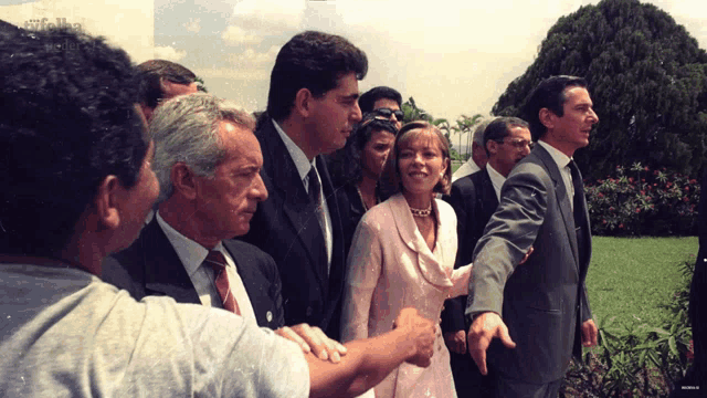 a woman in a pink dress stands in a crowd of men