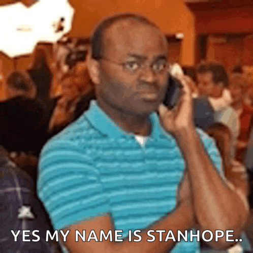 a man in a blue shirt is talking on a cell phone and says " yes my name is stanhope "