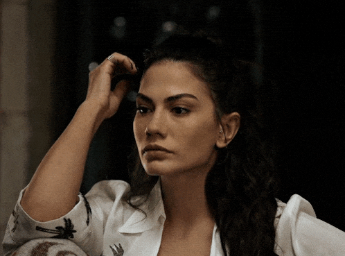 a woman in a white shirt with palm trees on the sleeves is touching her hair