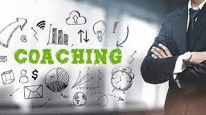 a man in a suit and tie is standing in front of a whiteboard with the word coaching .