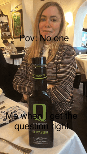 a woman sitting at a table with a bottle of olivastro olive oil