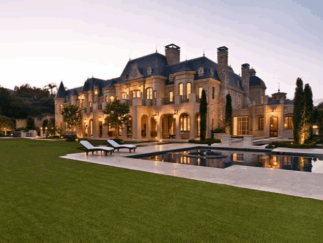 a large mansion with a swimming pool and chairs in front of it