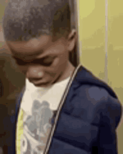 a young boy wearing a blue jacket and a t-shirt is standing in an elevator .