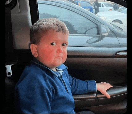 a little boy in a blue sweater is sitting in a car