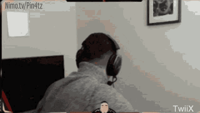 a man wearing headphones is sitting in front of a screen that says nimo.tv/pin4tz