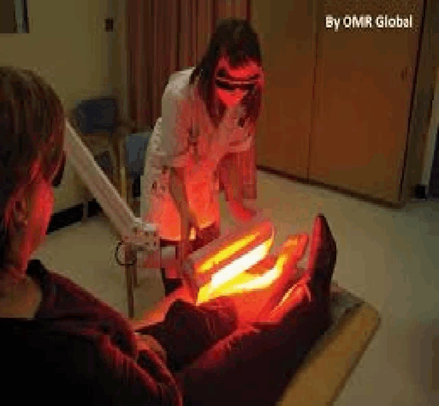 a woman is giving a person a red light treatment on their leg .