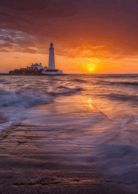 a lighthouse sits on the shore of the ocean at sunset