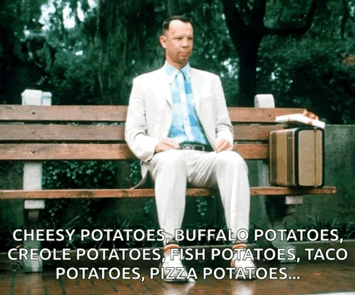 a man in a suit is sitting on a wooden bench with a suitcase and a pizza