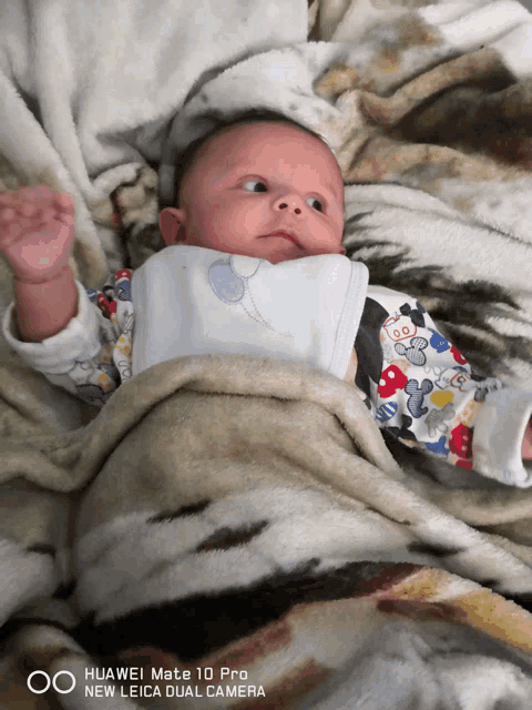 a baby is laying on a blanket with a huawei mate 10 pro camera