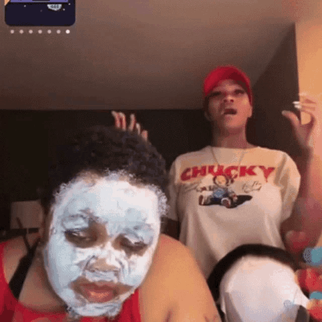 a woman wearing a chucky t-shirt stands next to another woman with a mask on her face