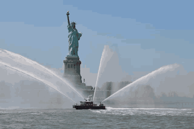 the statue of liberty is being sprayed with water by a boat