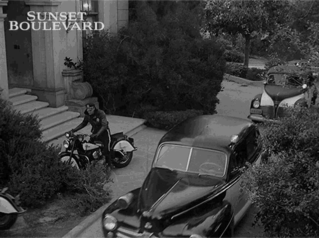 a black and white photo of a man riding a motorcycle in front of a building that says sunset boulevard