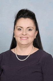 a woman wearing a pearl necklace and earrings is smiling .