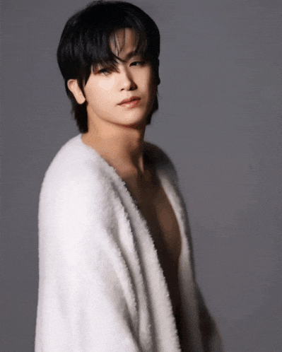 a young man without a shirt is wrapped in a white furry sweater